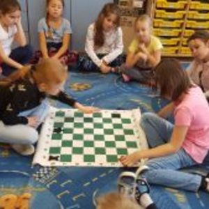 dwie osoby z klasy 2a grają w szachy a reszta klasy siedzi w kole i obserwuje.jpg