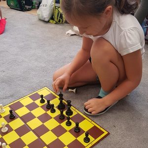Dziewczynka ustawia szachy na szachownicy.jpg