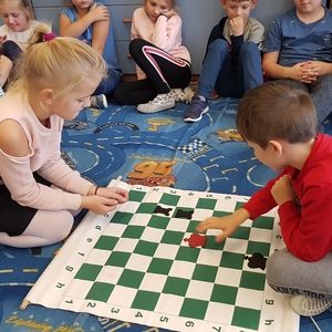 drugoklasiści grają w szachy na dywanie.jpg